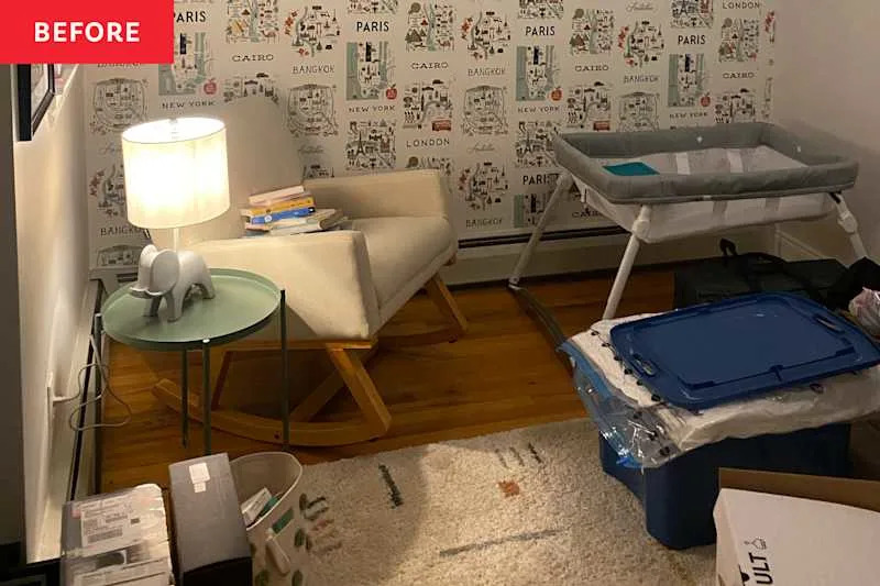 A cozy corner with a rocking chair, green side table, elephant lamp, and a bassinet, surrounded by boxes and books.