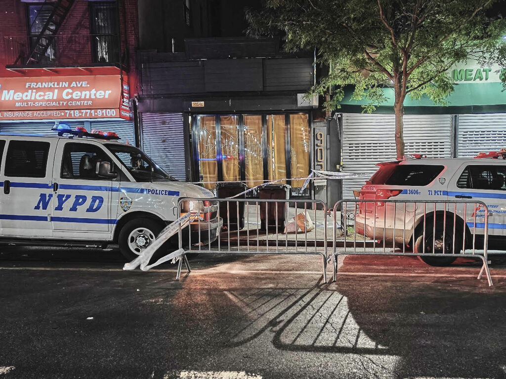New York City Police Department vehicles secure the entrance to the Taste of the City Lounge, center, where a shooting took place on Aug. 17 in Crown Heights. AP Photo/Julie Walker, File