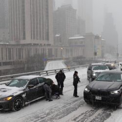 Police direct traffic past a car stuck going across the Brooklyn Bridge as it snows on Sunday, Jan. 25, 2026, in New York. Photo: Alyssa Goodman/AP