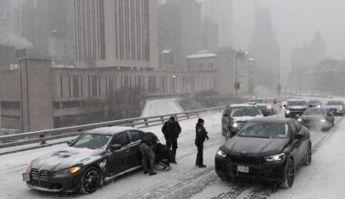 Police direct traffic past a car stuck going across the Brooklyn Bridge as it snows on Sunday, Jan. 25, 2026, in New York. Photo: Alyssa Goodman/AP