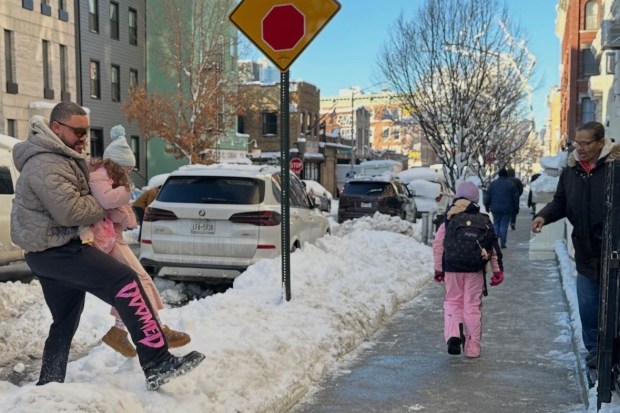 Students and parents in Brooklyn's Greenpoint neighborhood navigate around the snow on the way to school as classes resumed in New York on Tuesday, Feb. 24, 2026.  (AP Photo/Jake Offenhartz)