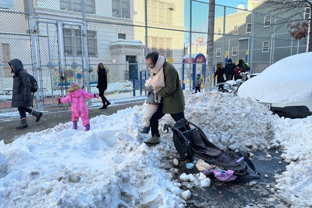 Students and parents in Brooklyn's Greenpoint neighborhood navigate around the snow on the way to school as classes resumed in New York on Tuesday, Feb. 24, 2026.  (AP Photo/Jake Offenhartz)