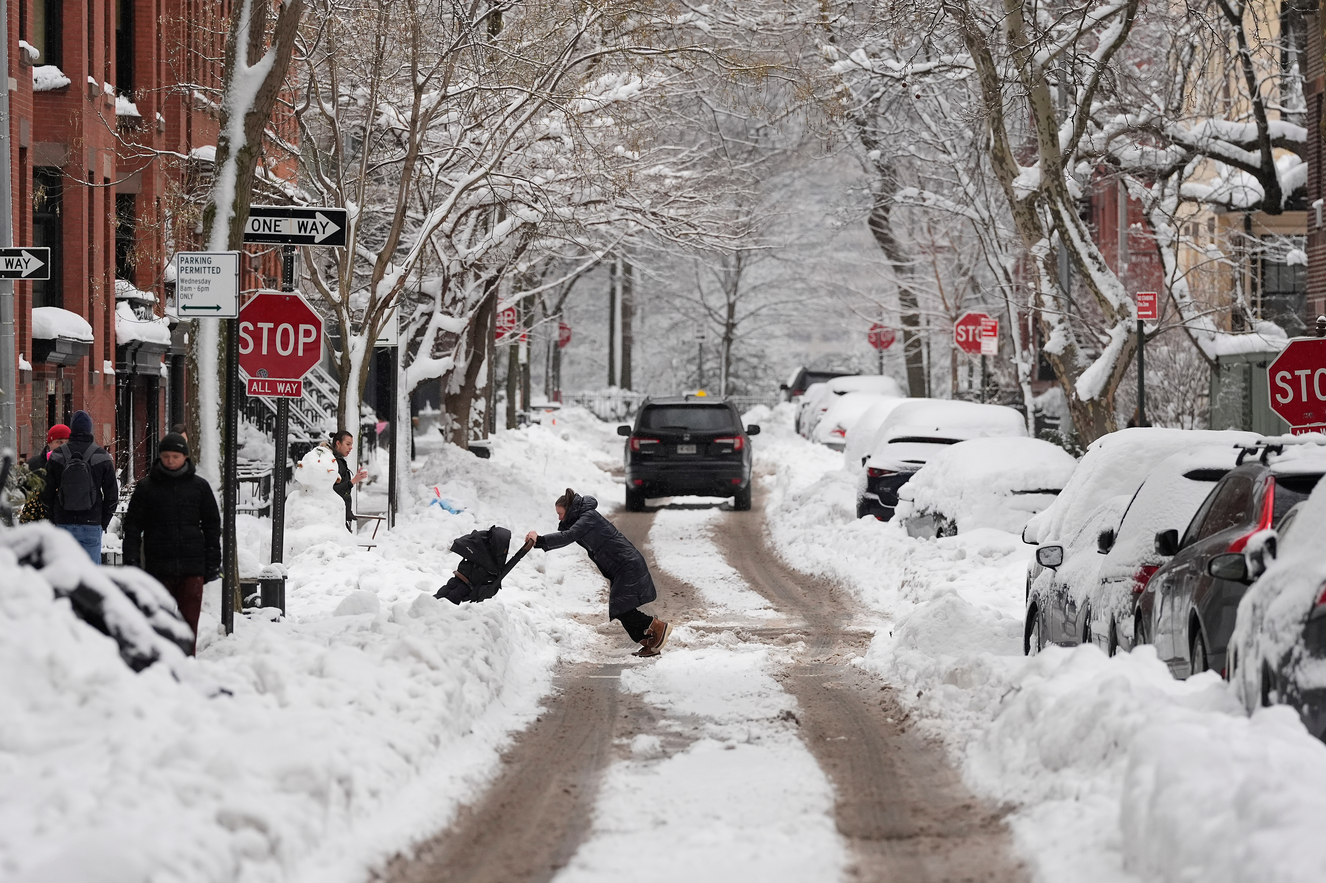 A woman pushes a stroller through plowed snow in Brooklyn.