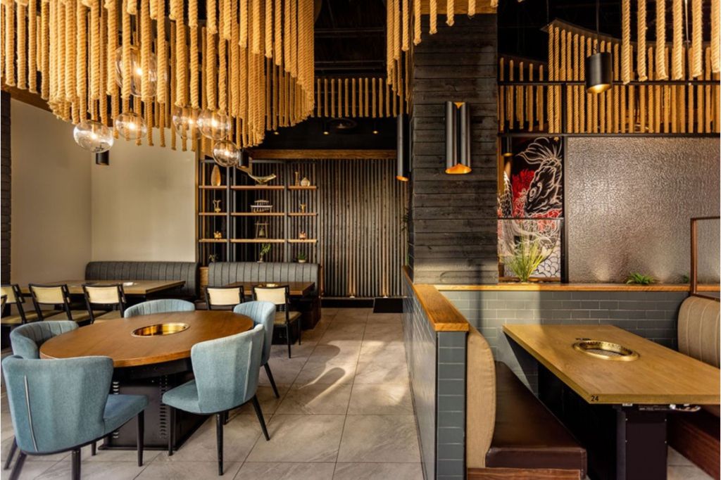 The interior of a restaurant with rope ceiling decor, light blue chairs, and dark gray booths.