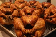 Fresh out of the rotisserie oven, a tray of golden brown seasoned chickens are ready to be...