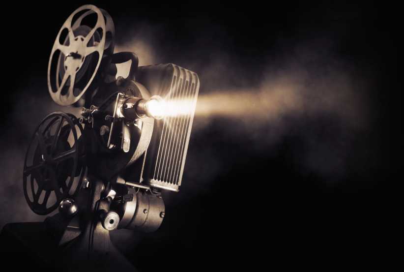 Movie projector on a dark background with light beam / high contrast image, indie movie theater NYC