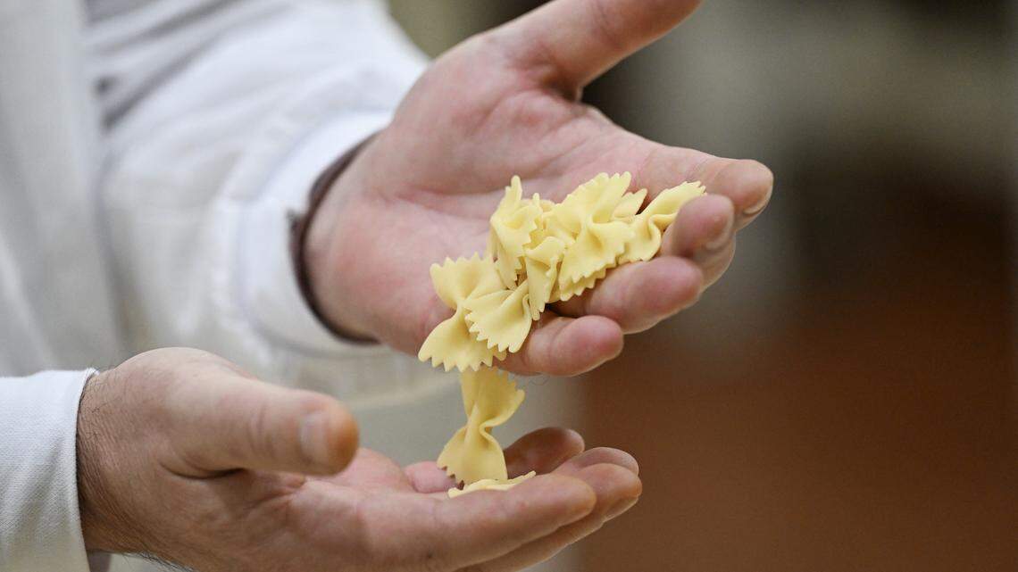 A man holds freshly made farfalle pasta.