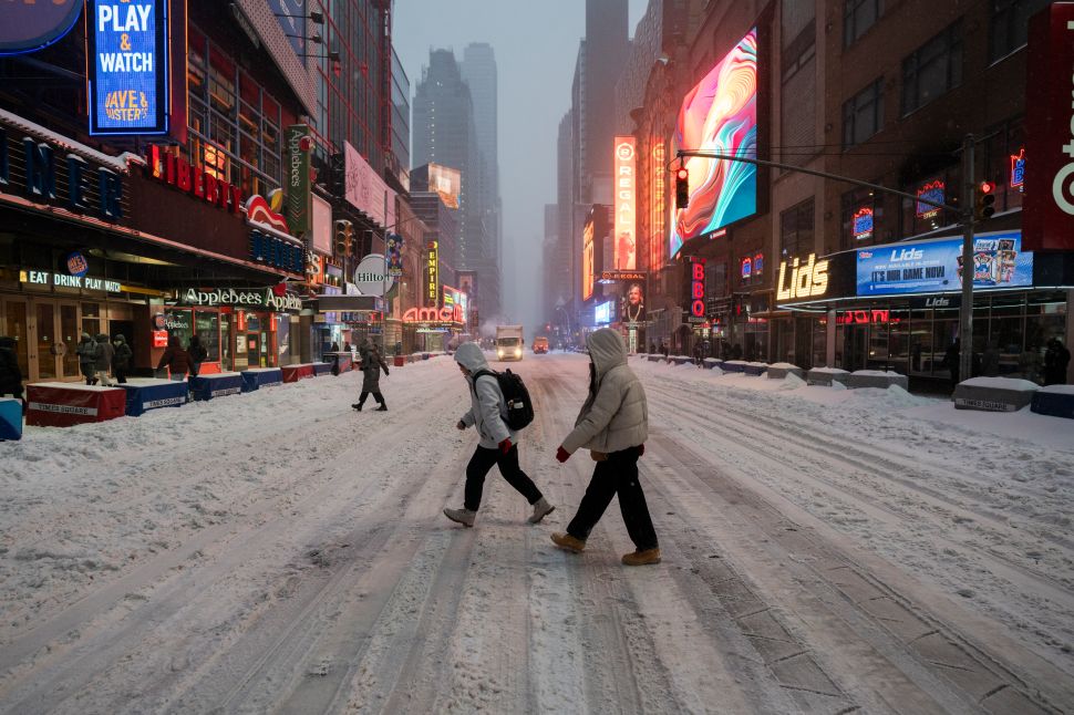 People walk through Times Square during a snowstorm on January 25, 2026 in New York City