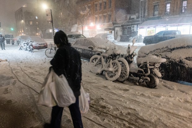 People walk through the streets as blizzard conditions arrive on Feb. 22, 2026, in the Brooklyn borough of New York City. Mayor Zohran Mamdani announced a state of emergency for the city and issued a travel ban beginning at 9 p.m. tonight through 12 p.m. tomorrow. New York City is expecting to get up to a foot of snow, with up to two feet on Long Island and in parts of New Jersey.