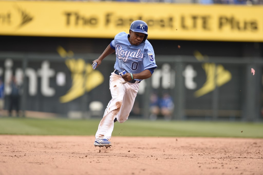 A Kansas City Royals player in a blue uniform with the number 0 runs on the baseball field.
