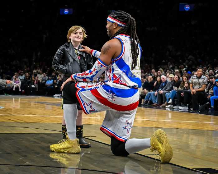 globetrotter kneeling with young fan