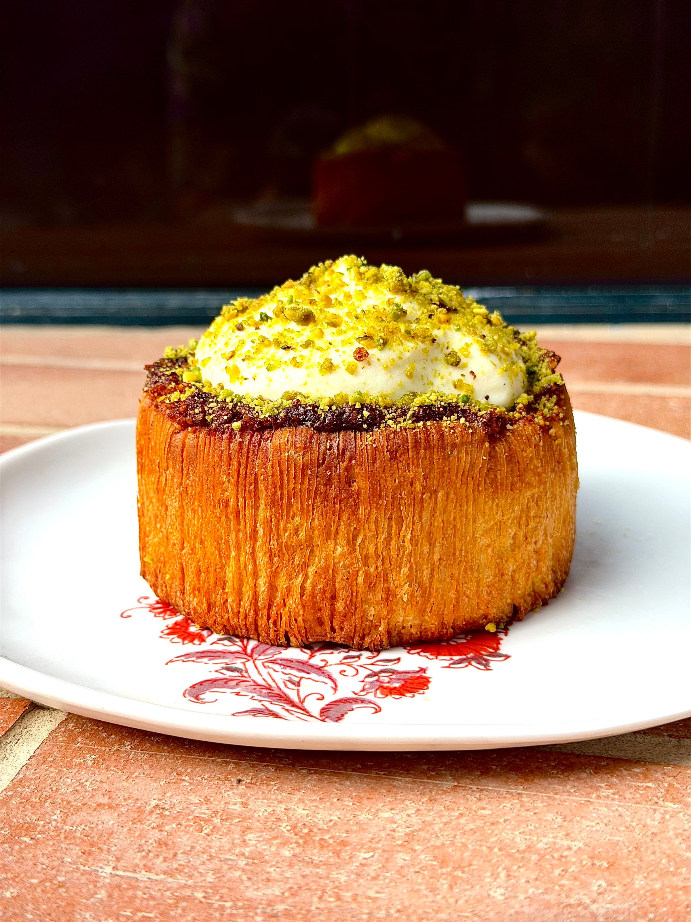 A tall round pastry with cream on top of it.