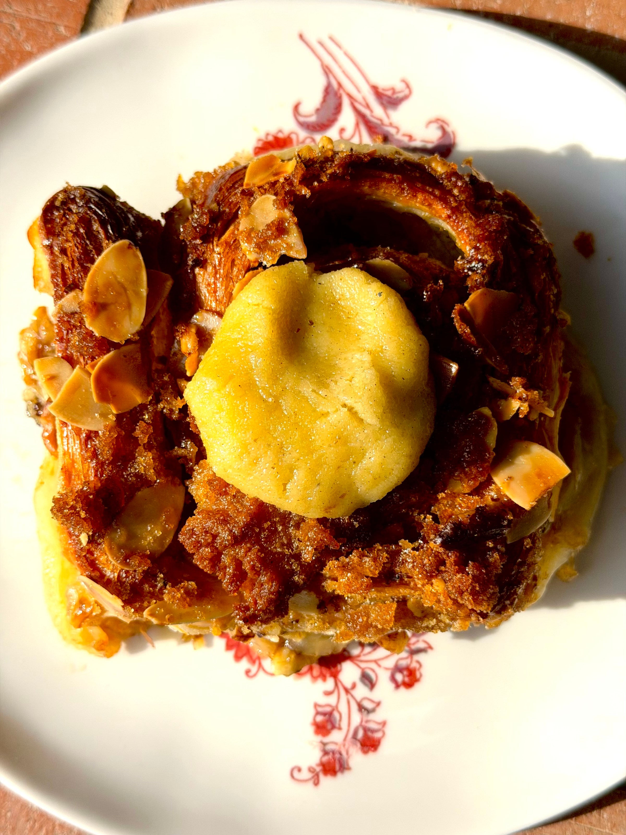 A bun dessert with yellow cream on top of it.