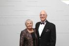 Claire and Bill Leggett dressed up and in front of a white donor wall. 