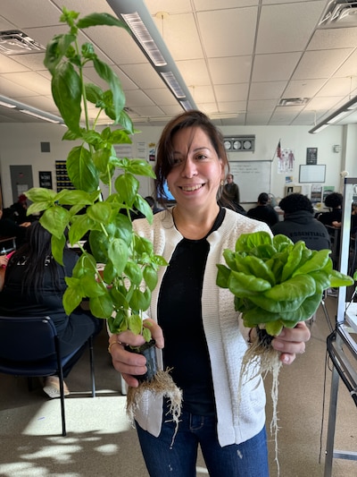 A woman poses for a portrait holding plantss.