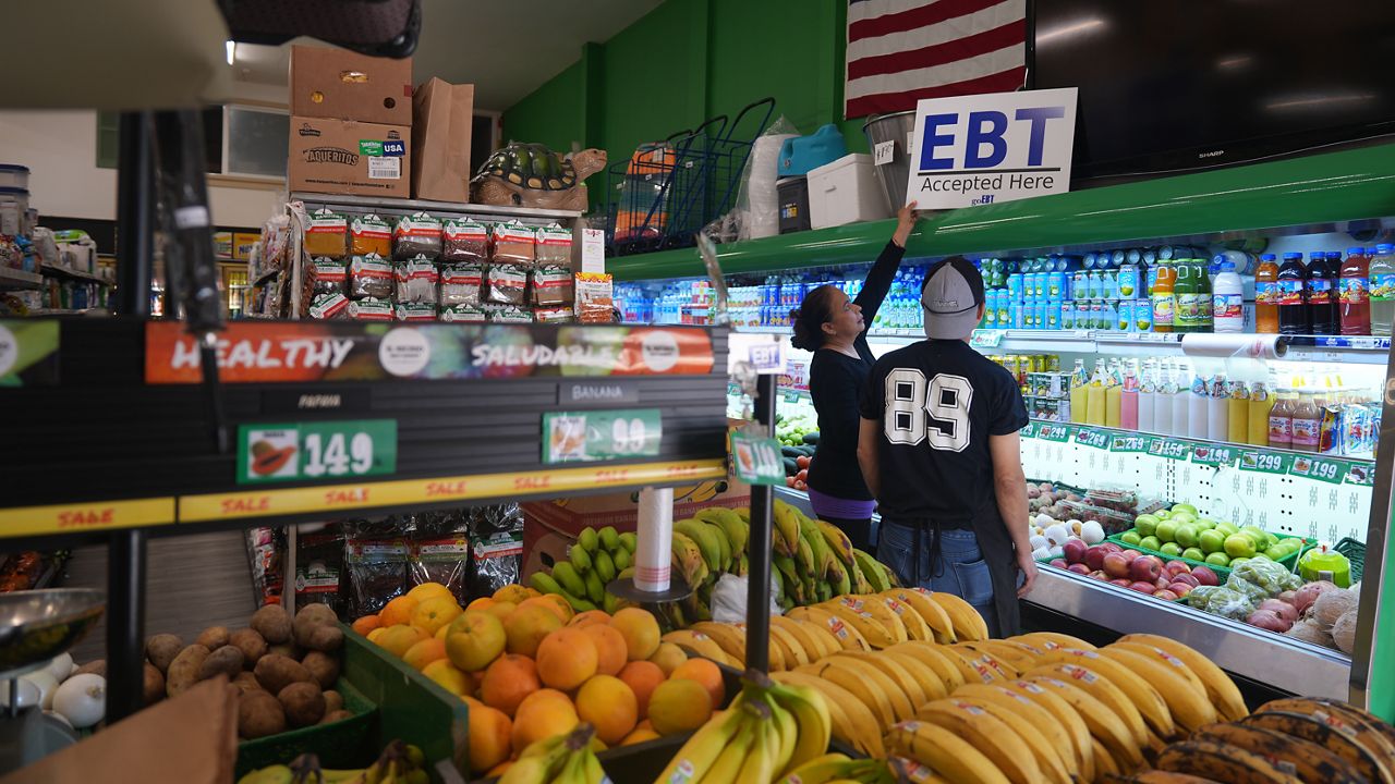 El Recuerdo Market manager Cecilia Benitez sets up a "EBT (Electronic Benefit Transfer) Accepted Here," banner