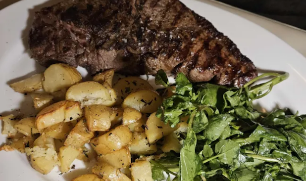 close up of a steak, potatoes, and salad on a plate