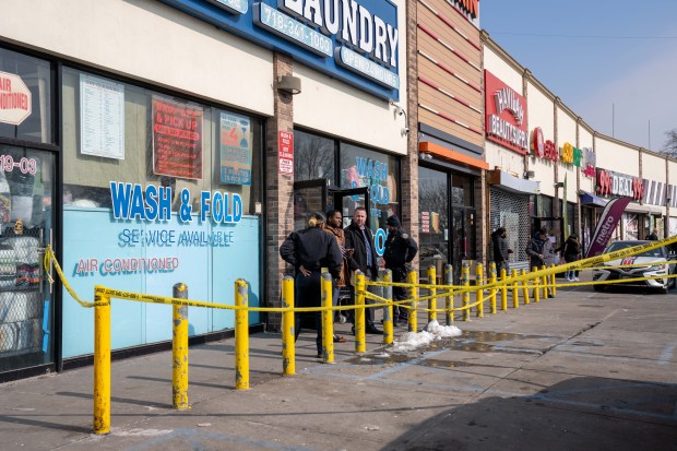 Police investigate the fatal shooting of Dominick Lowery outside a Queens laundromat on Saturday. 