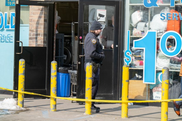 Police investigate the fatal shooting of Dominick Lowery outside a Queens laundromat on Saturday. 