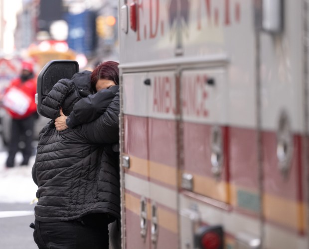 An FDNY EMT comforts a homicide witness as NYPD detectives and officers investigate a fatal shooting inside a 7-Eleven at the corner W. 39th St. and 8th Ave. in Manhattan on Thursday, Feb. 11, 2026. (Barry Williams/ New York Daily News)