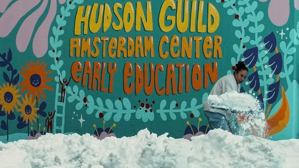 A woman clears snow from a walk outside a preschool, Tuesday, Feb. 24, 2026, in New York. (AP Photo/Eduardo Munoz Alvarez)