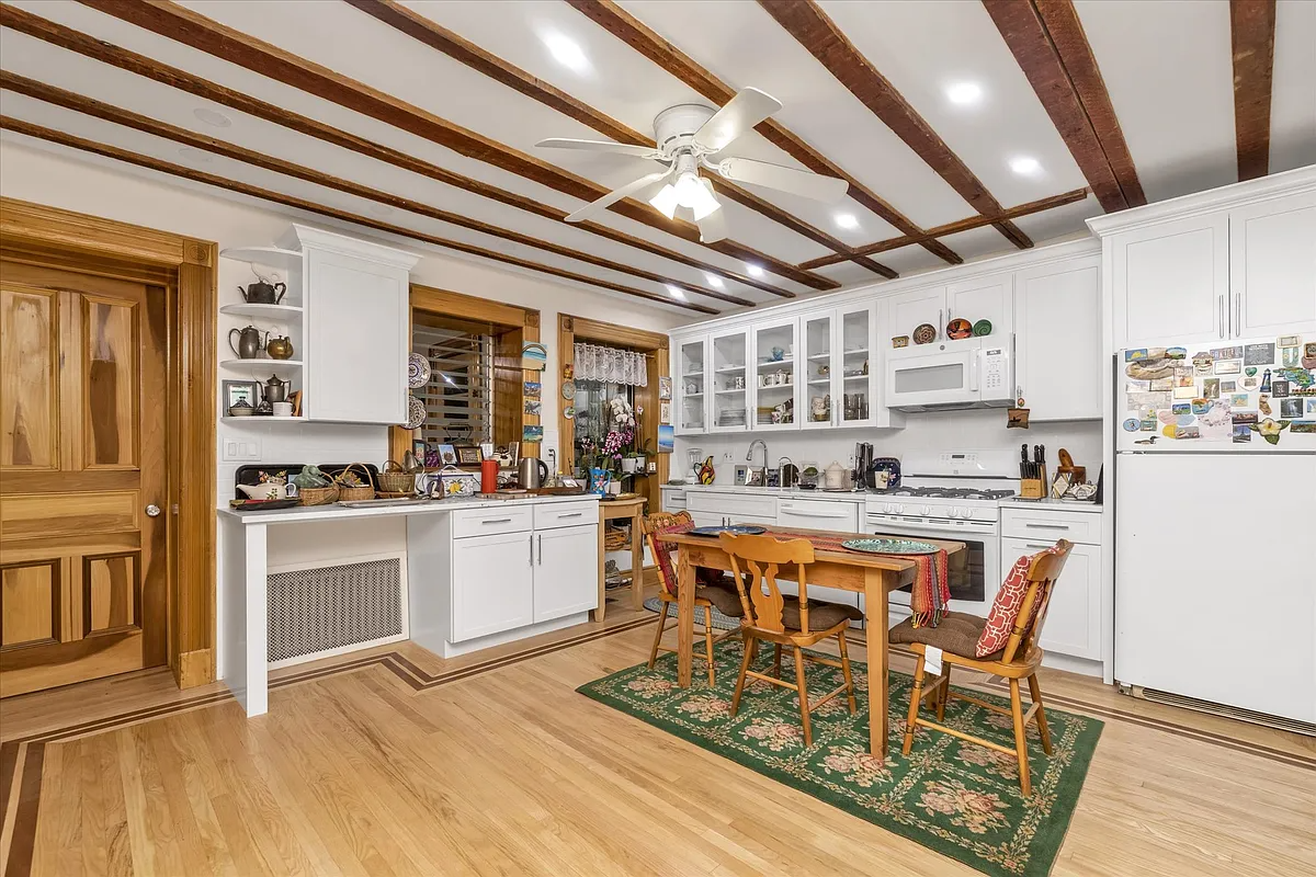 eat-in kitchen with wood floor, white cabinets