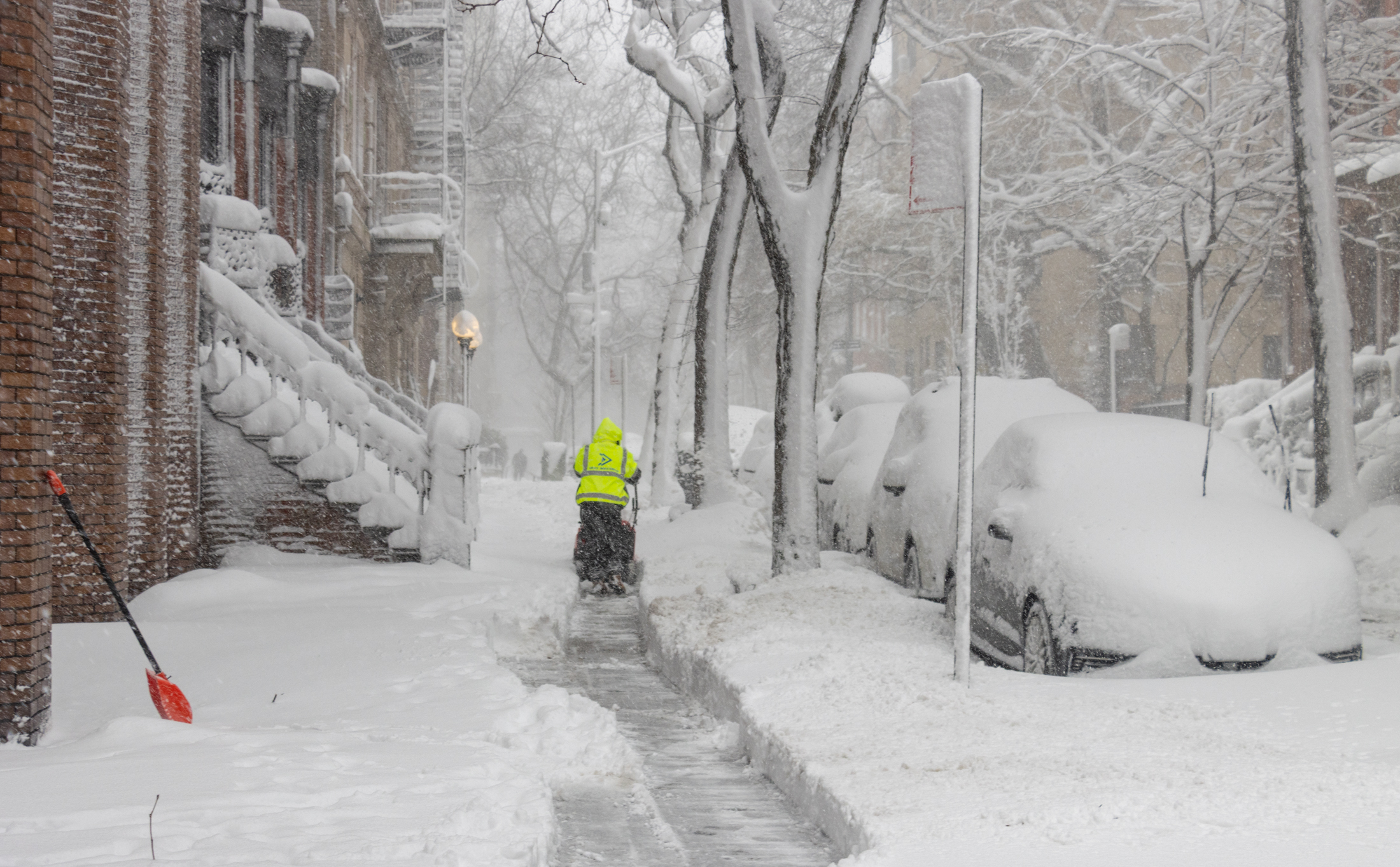 person snowblowing a sidewalk