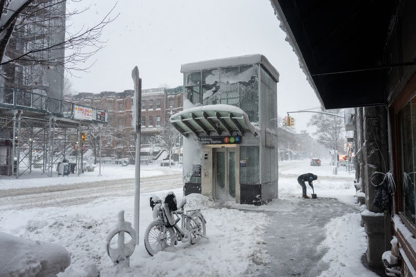 A person shovels the sidewalk amid heavy snow on February 23, 2026 in the Brooklyn borough of New York City