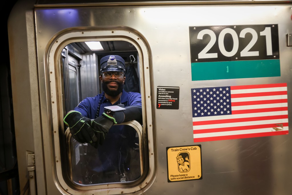 Calvin, a subway conductor, leaning out of the window of a train.
