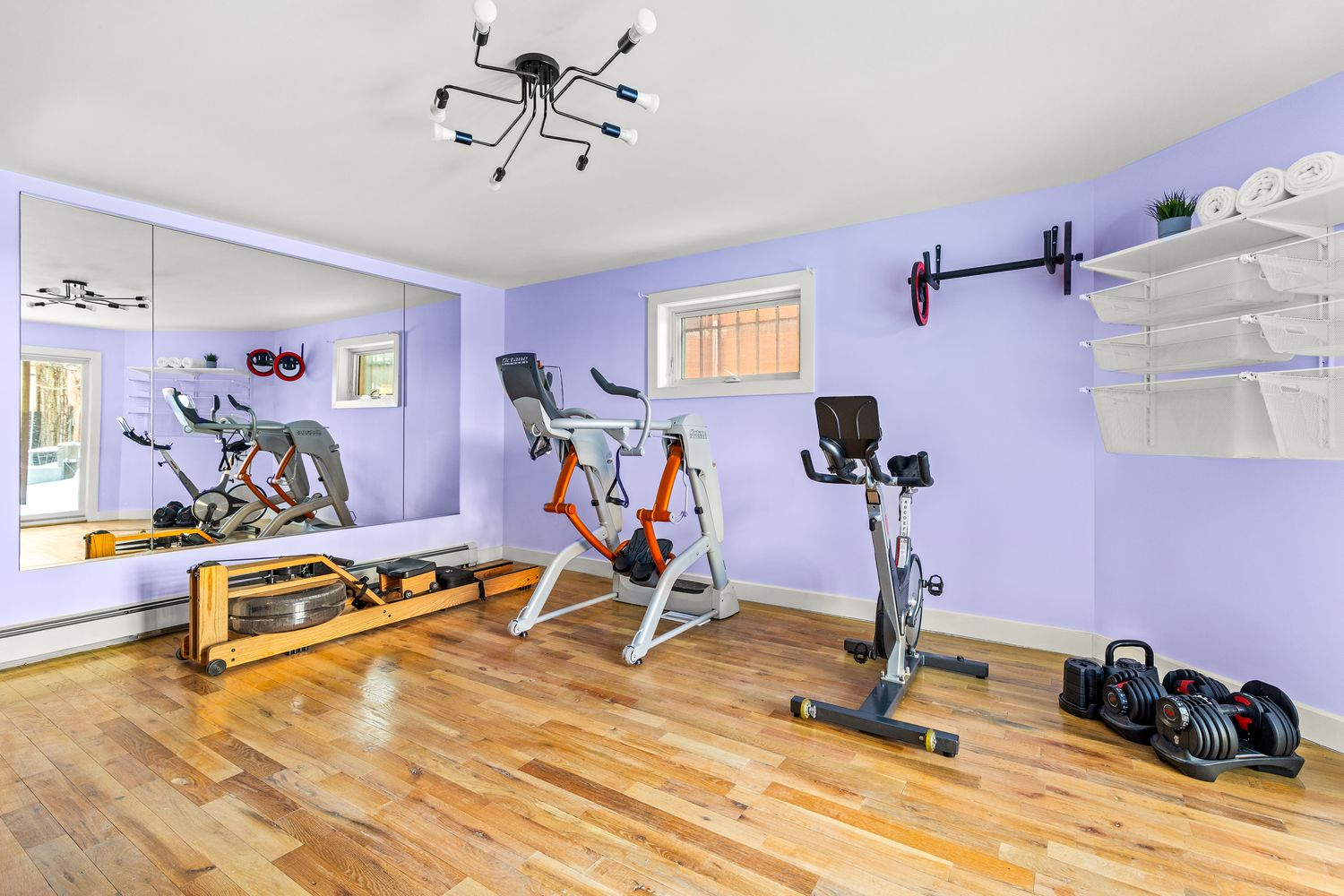bedroom set up as a gym with purple walls, wall of mirrors