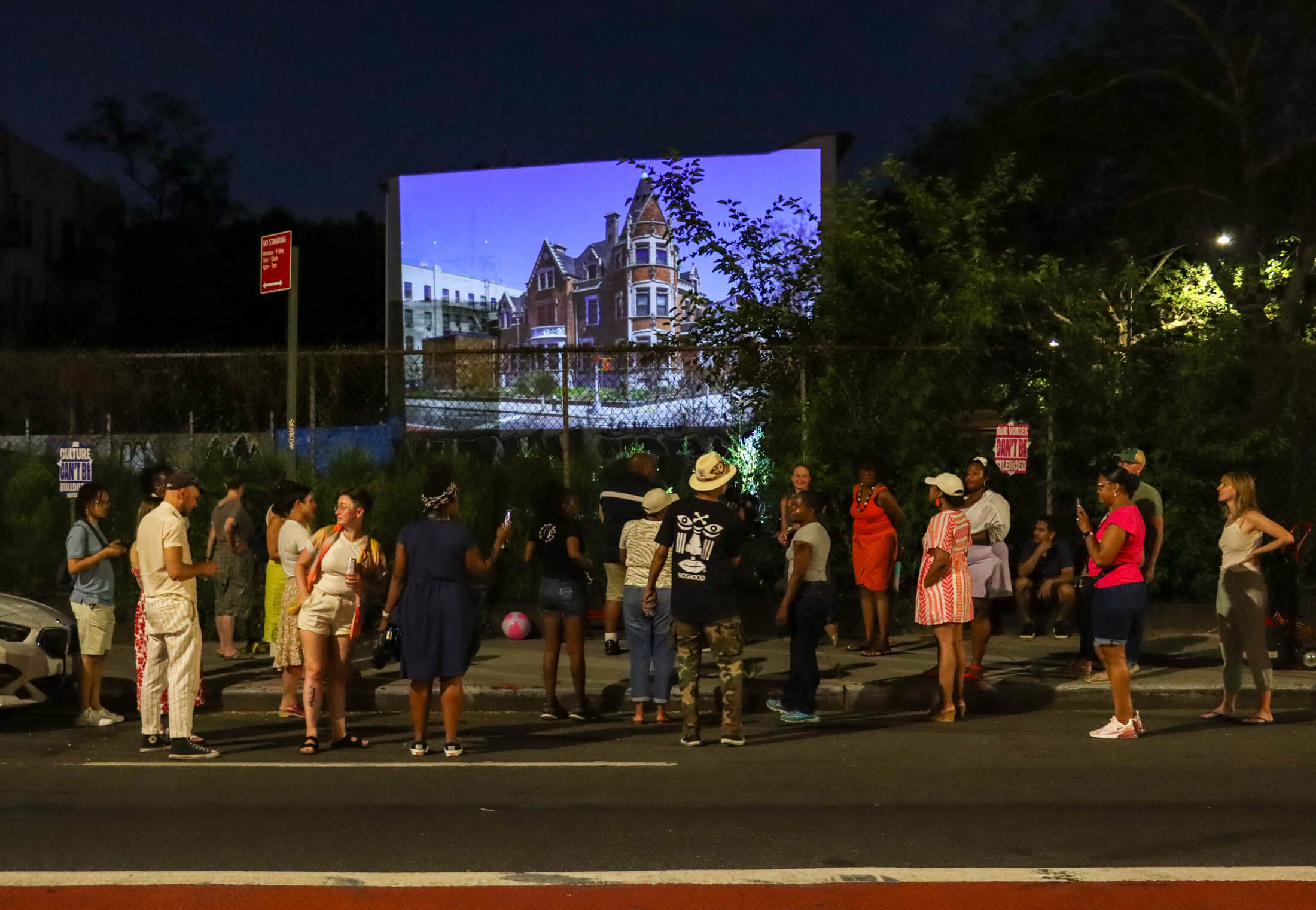 group outside the site of the dangler mansion at night looking at a projection of the demolished mansion