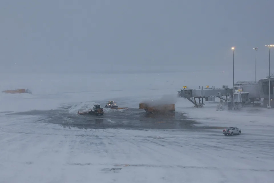Shannon Stapleton/Reuters - PHOTO: Snow plows clear snow from the tarmac during a winter storm at LaGuardia Airport in New York, Feb. 23, 2026.
