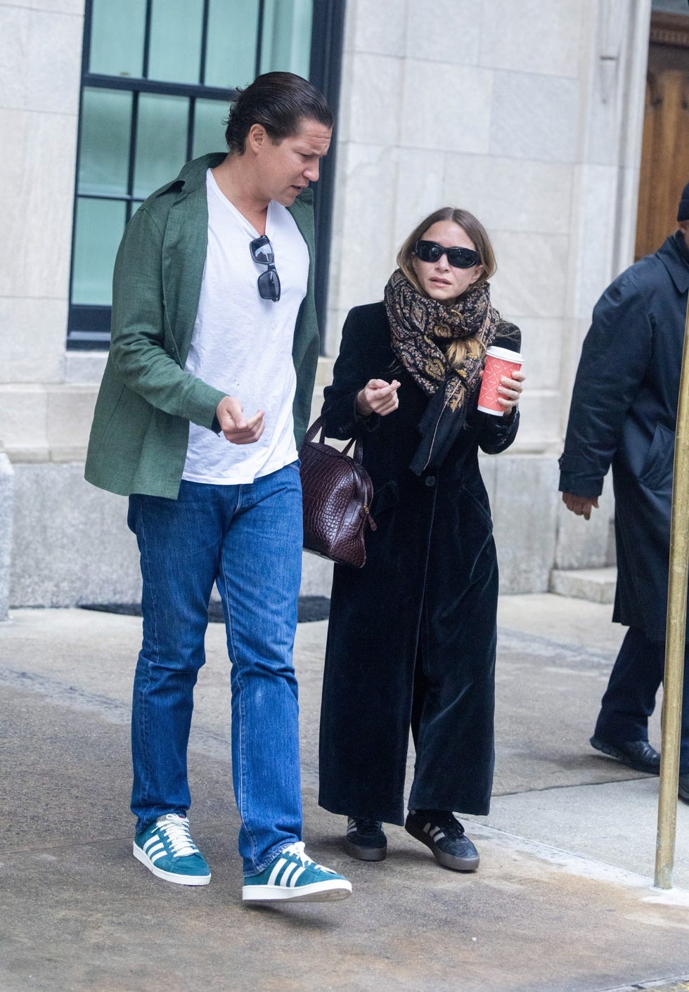 two individuals walking together on a city street one holding a beverage two individuals walking together on a city street one holding a beverage