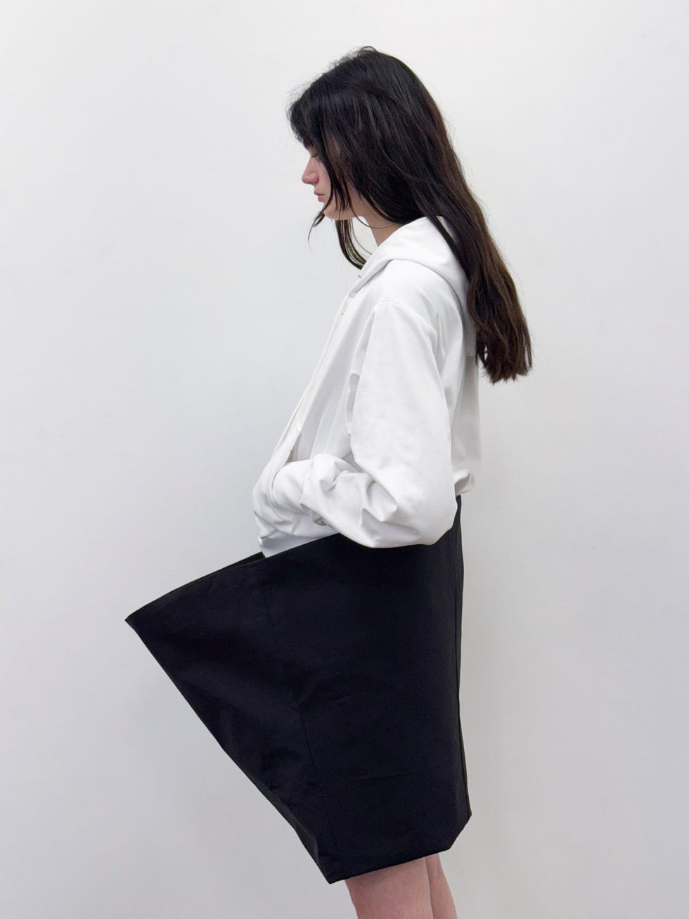 Side view of a person wearing a white shirt and a black skirt.