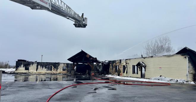 The demolished Abundant Life Fellowship church with fire hoses spraying water.