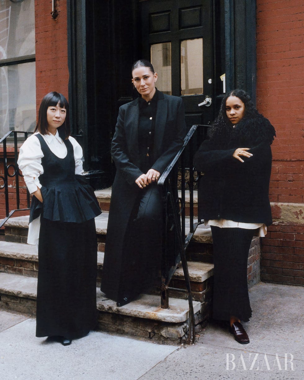 three individuals posing on steps in fashionable attire