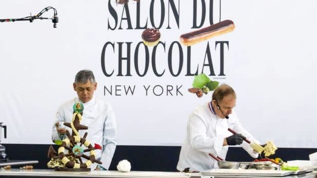 Two chefs in white coats work on intricate chocolate creations at the Salon du Chocolat in New York.