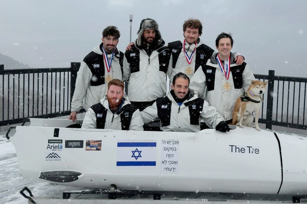 Members of Israel's Winter Olympics bobsleigh team, with Adam “AJ” Edelman (right), posing with their bobsled and a dog.