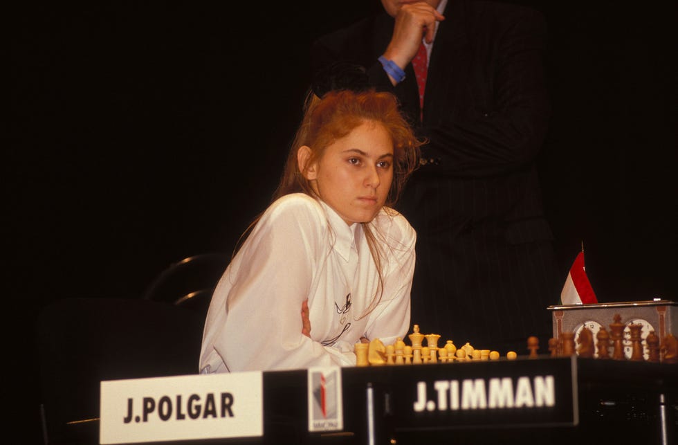 teenage girl sitting at a chess board with large name cards on the table