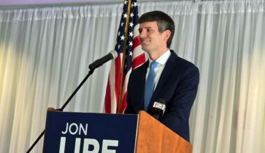 jon lipe smiles behind a podium