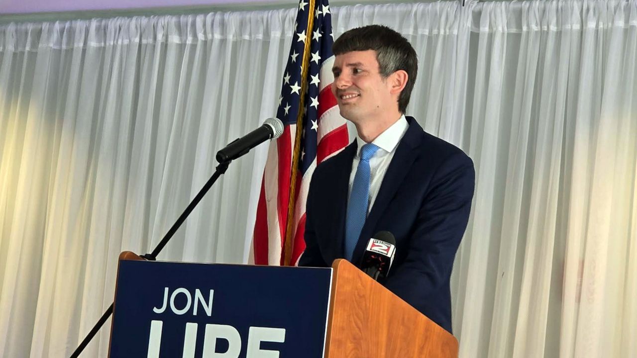 jon lipe smiles behind a podium
