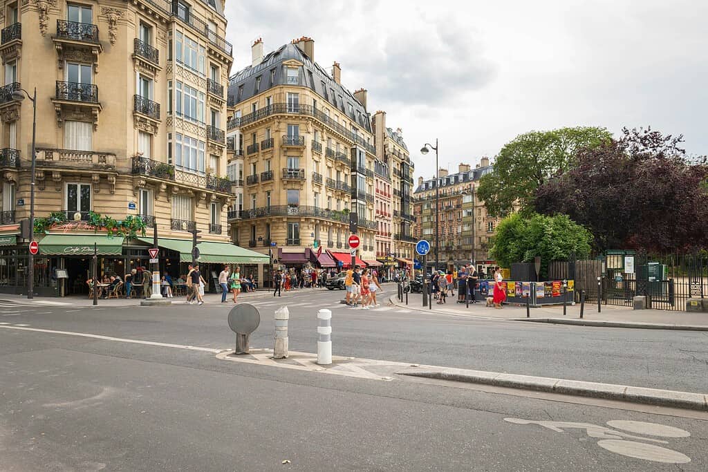 Paris street scene with historic buildings, cafe terraces, and pedestrians; urban landscape.