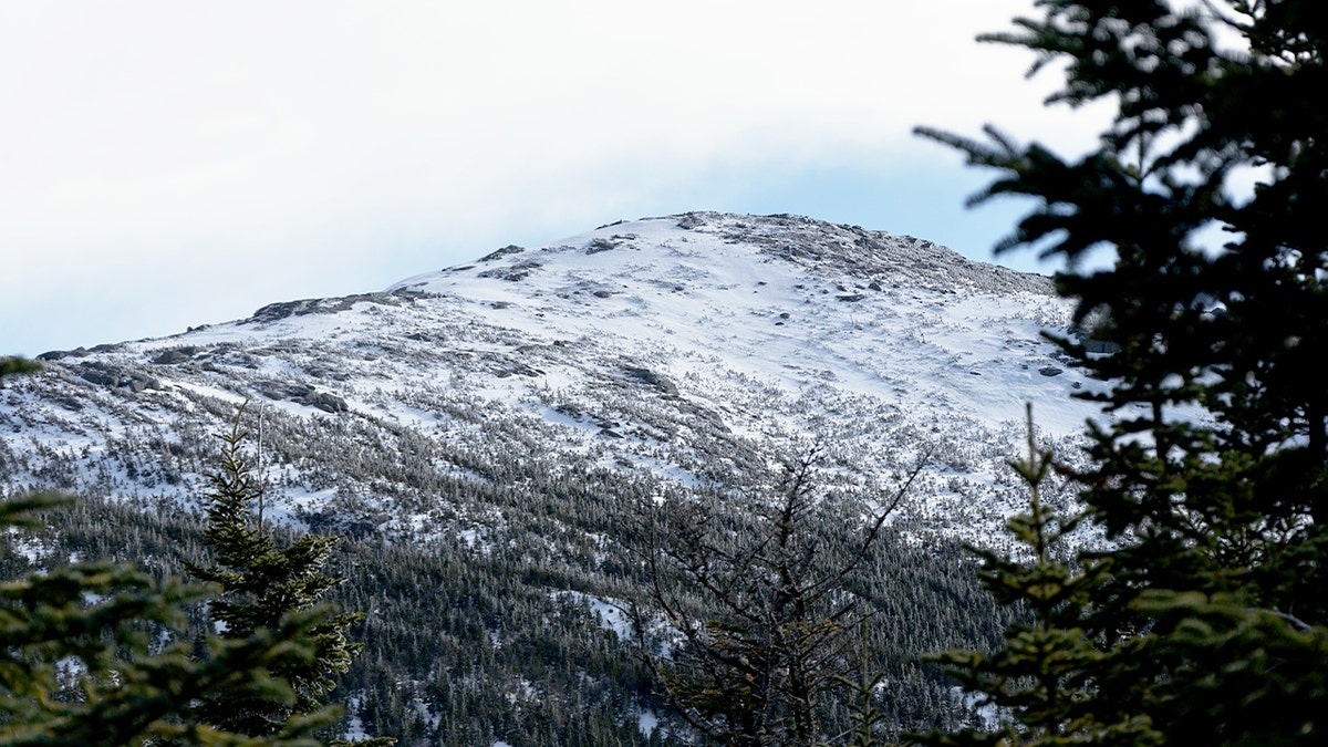Snow-covered alpine peak glows in soft evening light after a backcountry ski descent.
