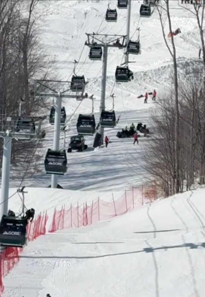 Rescue workers on a snowy mountain assisting stranded skiers from a gondola lift.