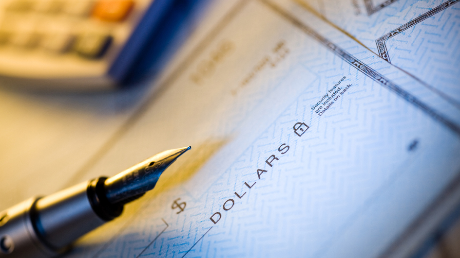 Partial image of a fountain pen sitting on top of a blank check