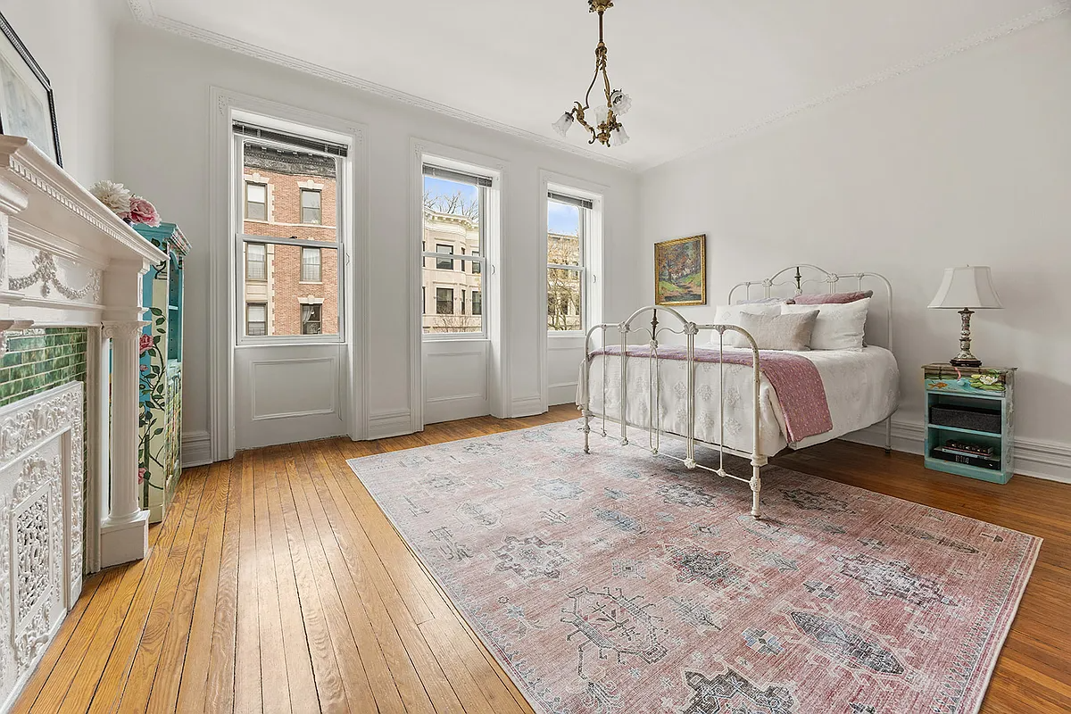 bedroom with white columned mantel, wood floor