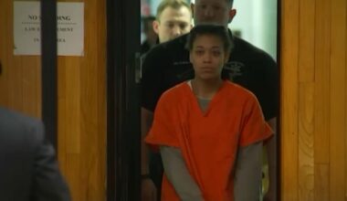 persia nelson enters a courtroom in orange jail clothing
