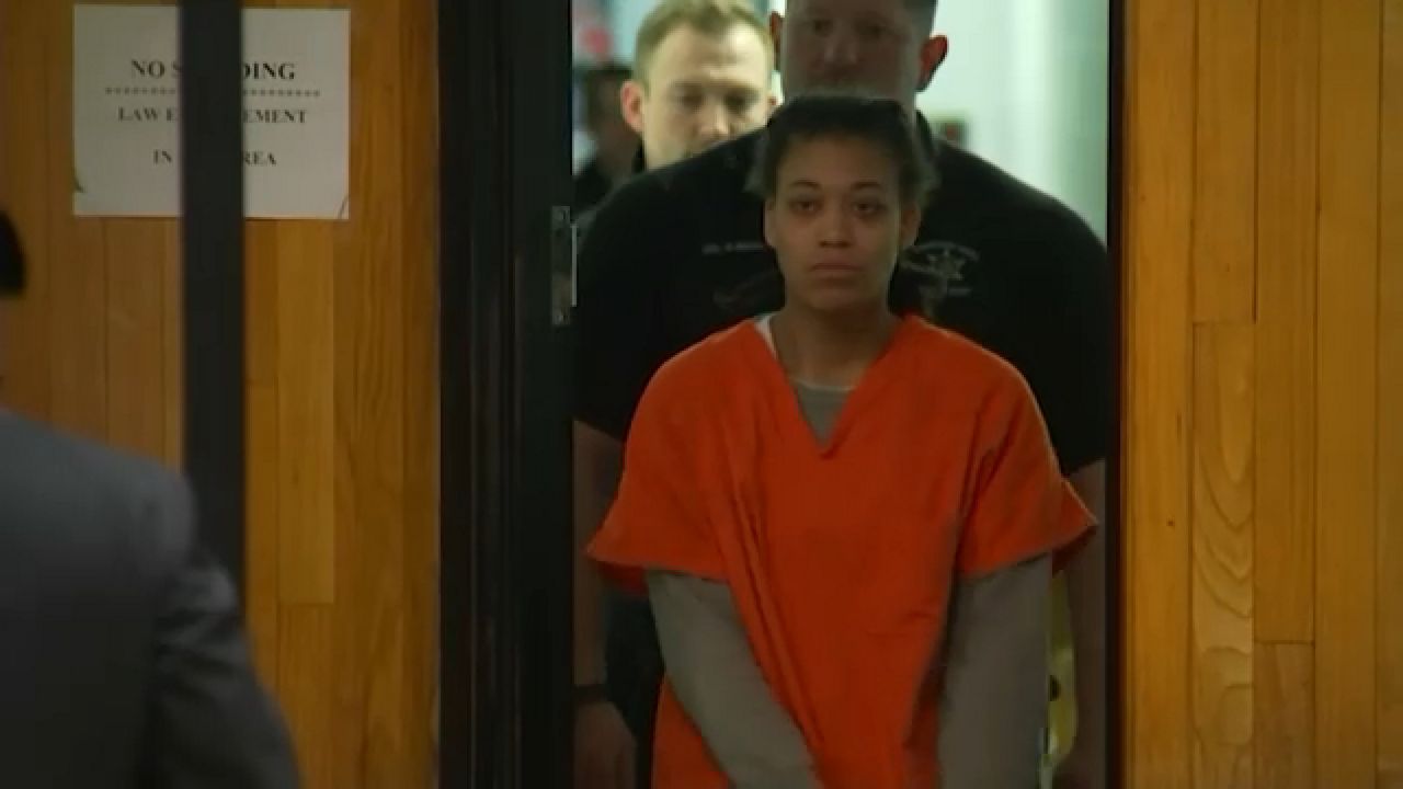 persia nelson enters a courtroom in orange jail clothing