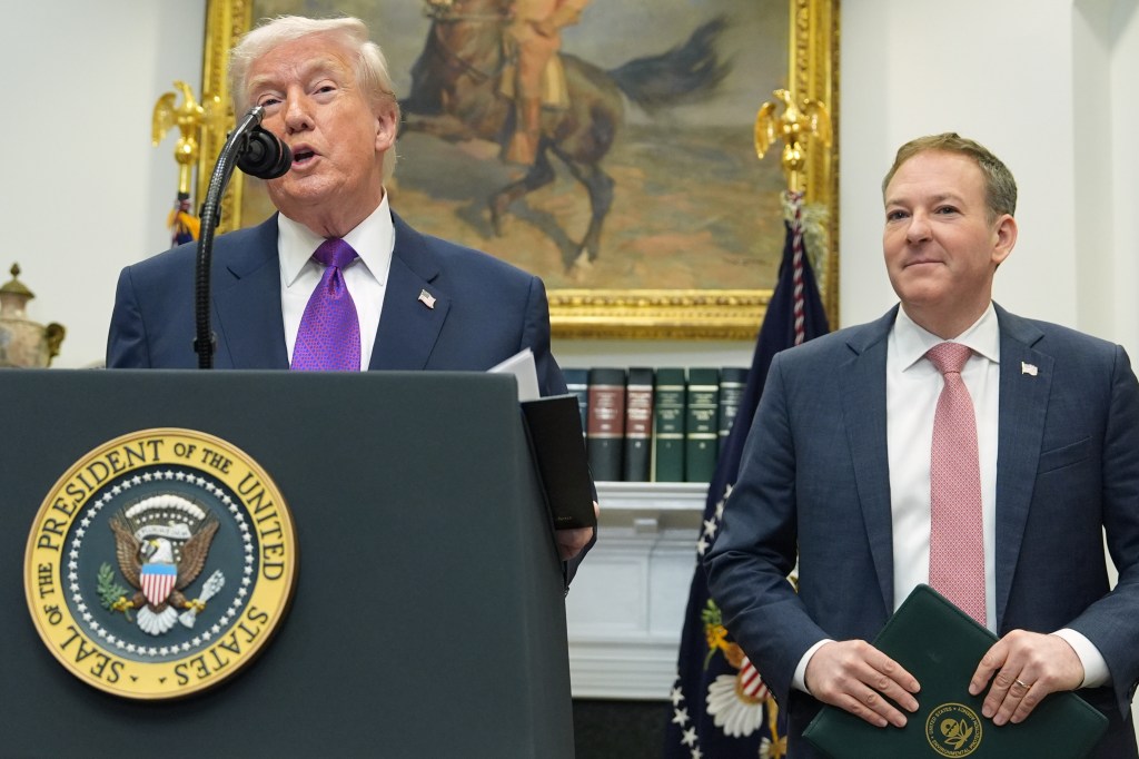 Donald Trump speaks at a podium with the Presidential Seal, next to Lee Zeldin, EPA Director, holding a green folder.