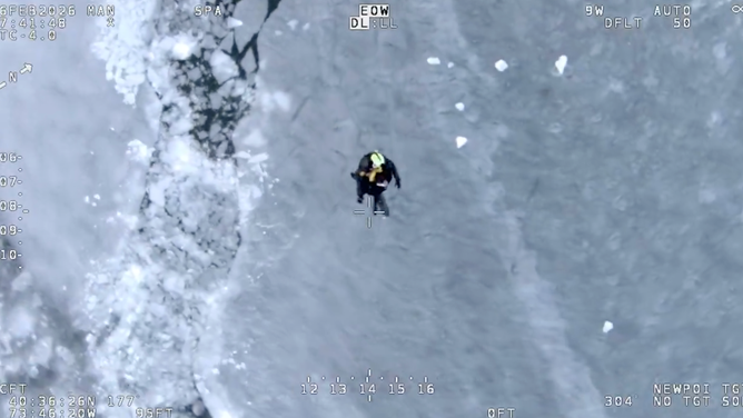 A rescuer repels with a person pulled from ice to dry land.